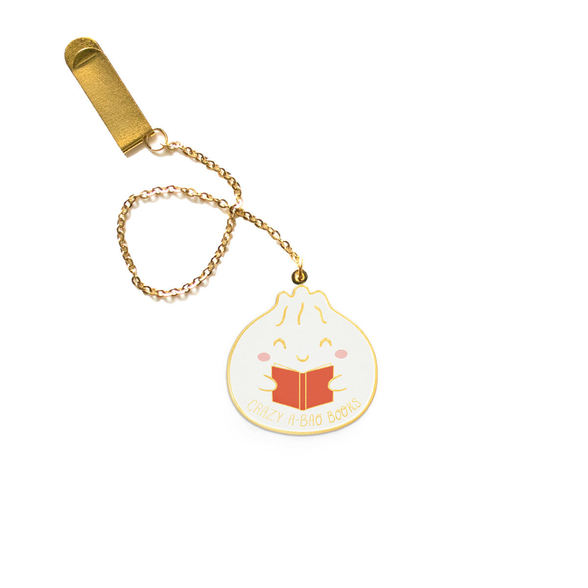 An enamel pendant shaped like a soup dumpling with a smiling face, pink cheeks and little hands holding a red book. Attached to a gold chain and gold clip that clips to any page of a book.